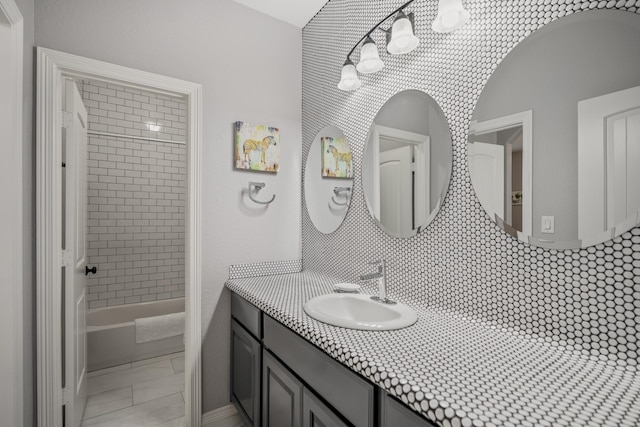 bathroom featuring decorative backsplash, vanity, and tiled shower / bath