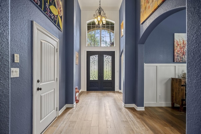 entrance foyer featuring hardwood / wood-style floors, a notable chandelier, and french doors