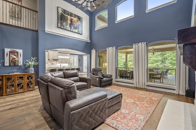 living room with hardwood / wood-style floors, a notable chandelier, and a towering ceiling