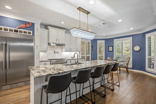 kitchen with white cabinetry, sink, dark hardwood / wood-style floors, stainless steel built in fridge, and a center island with sink