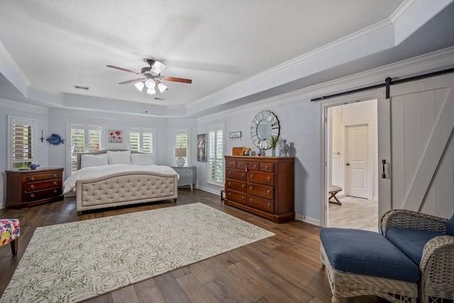 bedroom featuring a tray ceiling, a barn door, ceiling fan, and dark hardwood / wood-style flooring