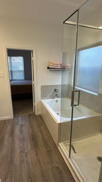 bathroom with plus walk in shower and hardwood / wood-style flooring