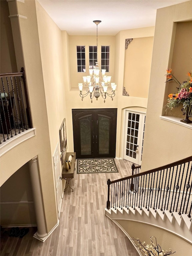 entrance foyer featuring french doors, hardwood / wood-style floors, and an inviting chandelier