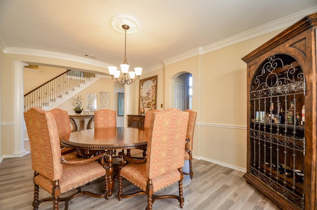 dining space featuring light hardwood / wood-style flooring, an inviting chandelier, and ornamental molding