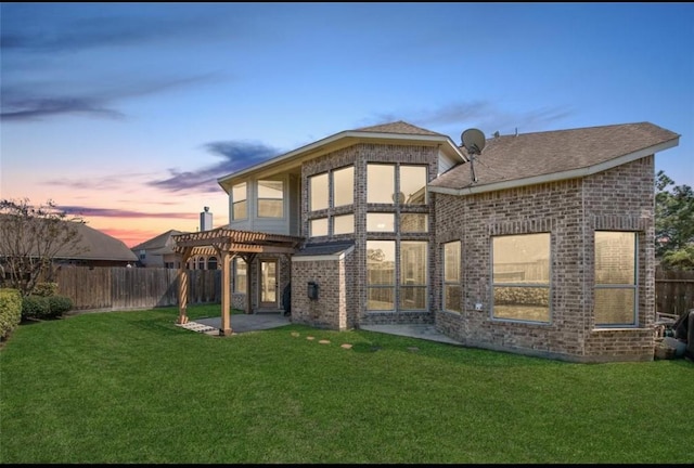 back house at dusk with a pergola, a yard, and a patio