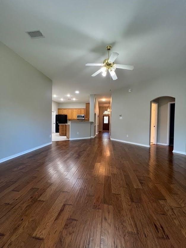 unfurnished living room featuring ceiling fan and dark hardwood / wood-style flooring