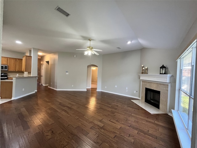 unfurnished living room featuring ceiling fan, a fireplace, dark wood-type flooring, and vaulted ceiling