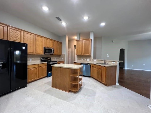 kitchen featuring sink, kitchen peninsula, a kitchen island, black appliances, and light wood-type flooring