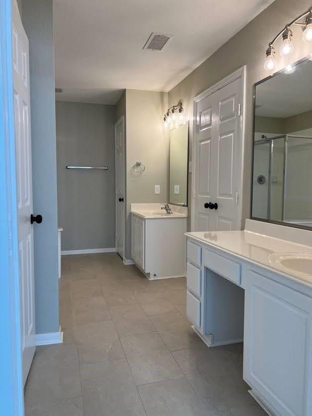 bathroom with tile patterned flooring, vanity, and a shower with door