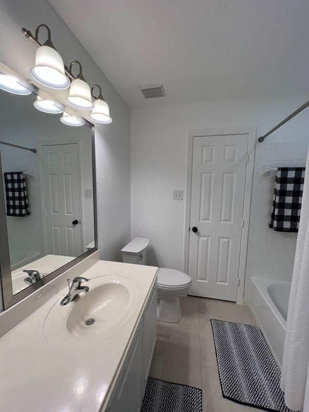 full bathroom featuring tile patterned floors, shower / bath combo with shower curtain, vanity, and toilet