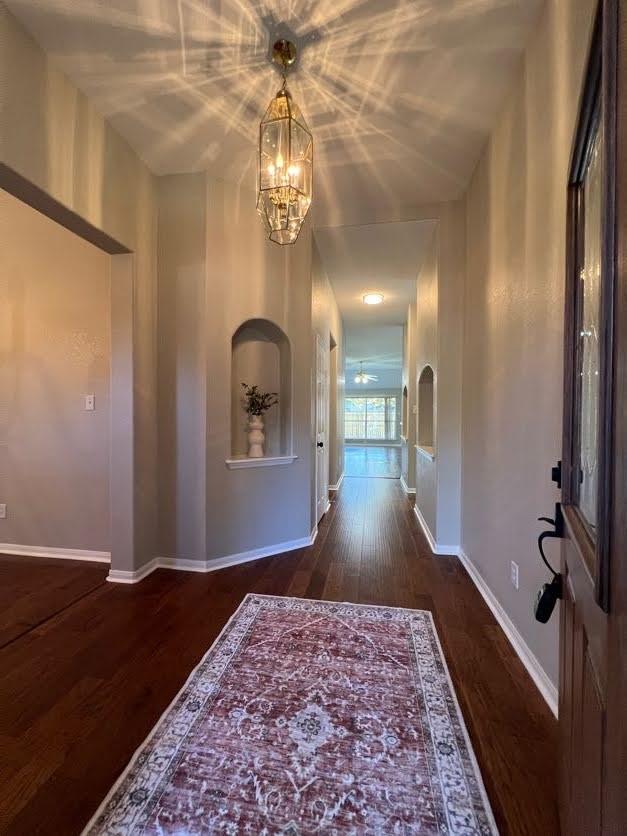 hall with dark hardwood / wood-style flooring and an inviting chandelier