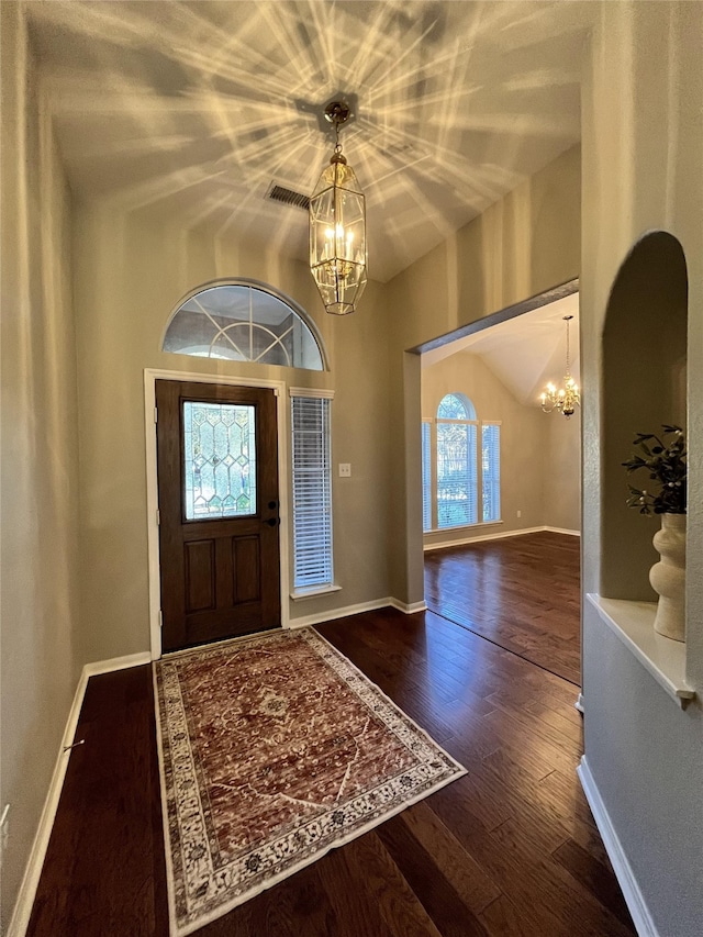 entrance foyer featuring hardwood / wood-style floors, lofted ceiling, and a notable chandelier