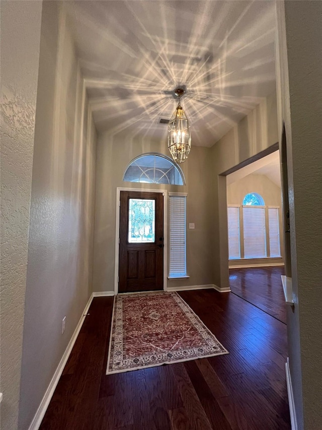 entryway featuring dark wood-type flooring and an inviting chandelier