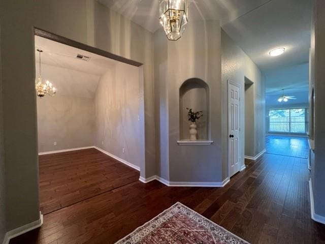 corridor featuring lofted ceiling, dark hardwood / wood-style flooring, and a notable chandelier