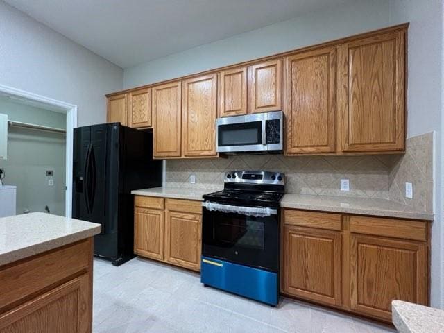 kitchen featuring washer / dryer, backsplash, and black appliances