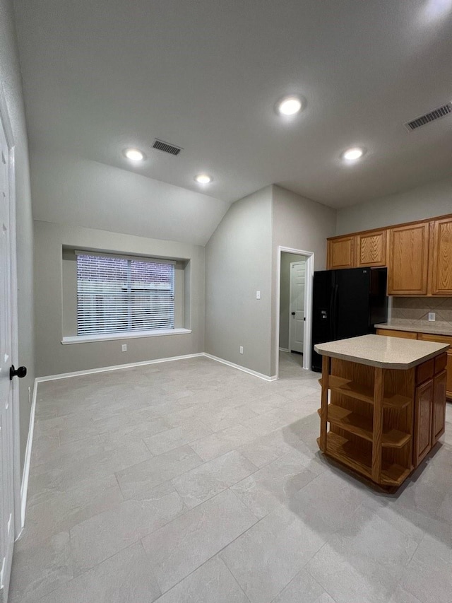 kitchen featuring a kitchen island, light tile patterned floors, lofted ceiling, and black refrigerator with ice dispenser