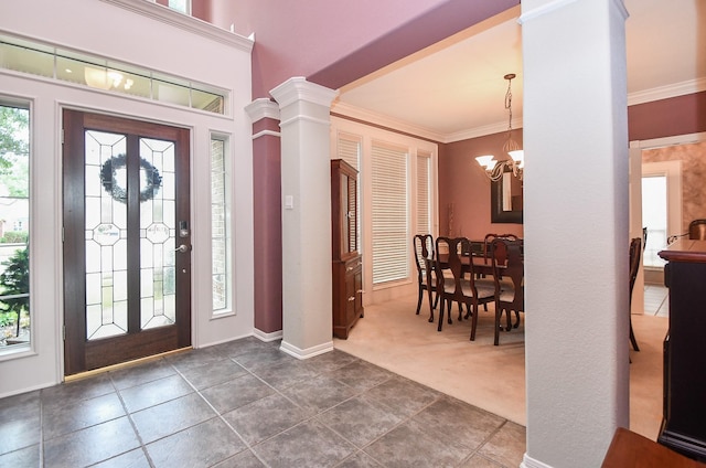 carpeted entrance foyer featuring decorative columns, crown molding, and an inviting chandelier