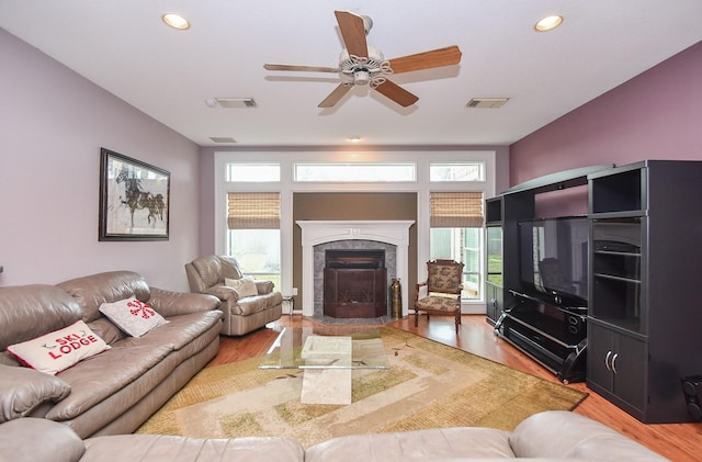 living room with a fireplace, wood-type flooring, and ceiling fan