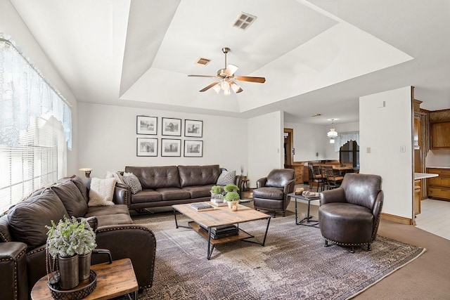 living room with a raised ceiling and ceiling fan