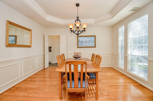 dining area with a tray ceiling, light hardwood / wood-style flooring, and plenty of natural light