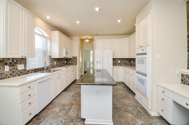 kitchen with white cabinets, a center island, white appliances, and sink