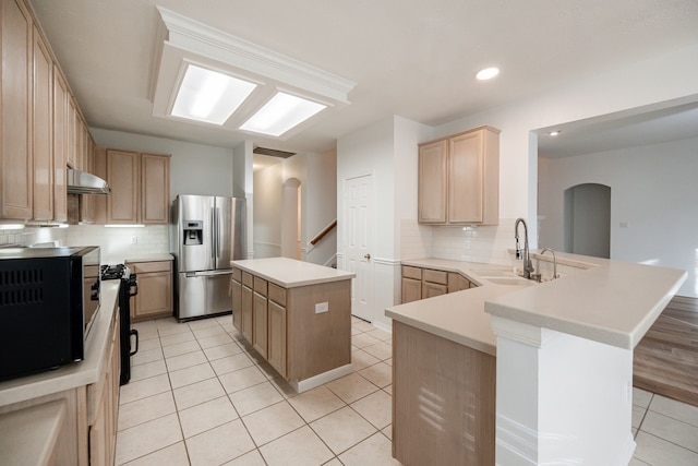 kitchen with sink, stainless steel fridge with ice dispenser, kitchen peninsula, light brown cabinetry, and a kitchen island