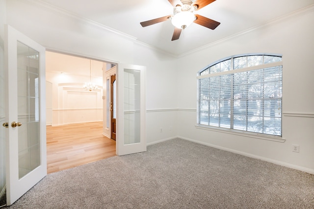 carpeted empty room with ceiling fan with notable chandelier, ornamental molding, and french doors