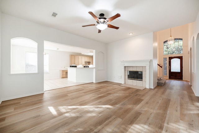 unfurnished living room with ceiling fan, a fireplace, and light hardwood / wood-style flooring