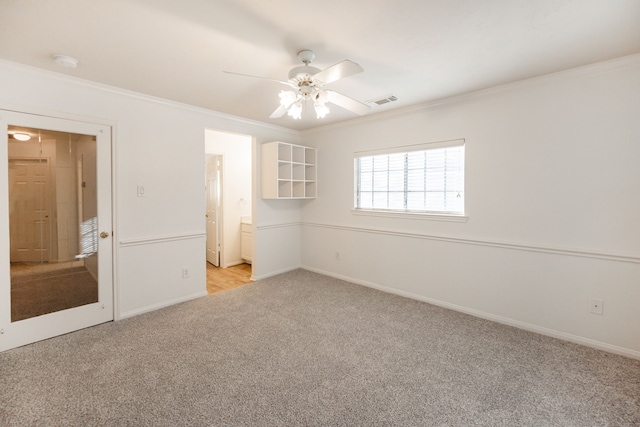 unfurnished bedroom featuring ceiling fan, light colored carpet, crown molding, and ensuite bath