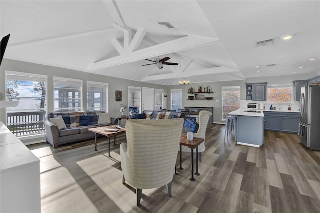 living room with vaulted ceiling with beams, a healthy amount of sunlight, dark hardwood / wood-style flooring, and ceiling fan with notable chandelier