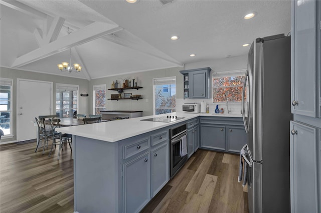 kitchen featuring kitchen peninsula, lofted ceiling with beams, stainless steel appliances, and dark wood-type flooring