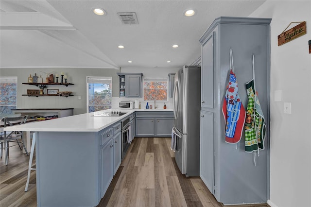 kitchen featuring gray cabinetry, stainless steel appliances, a kitchen breakfast bar, light hardwood / wood-style flooring, and a textured ceiling