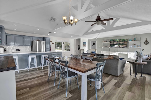 dining area featuring vaulted ceiling with beams, dark wood-type flooring, and ceiling fan with notable chandelier