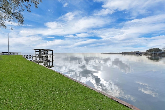 view of dock featuring a lawn and a water view