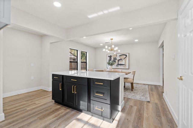 kitchen featuring light wood-type flooring, pendant lighting, a notable chandelier, beamed ceiling, and a kitchen island