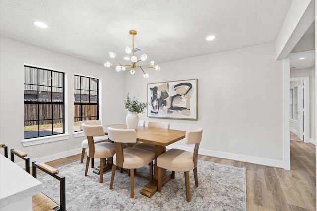 dining space featuring light hardwood / wood-style flooring, a chandelier, and a textured ceiling