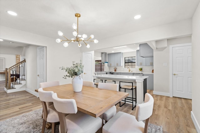 dining area with a chandelier, sink, and light hardwood / wood-style flooring