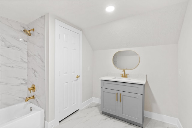 bathroom with vanity, lofted ceiling, and tiled shower / bath