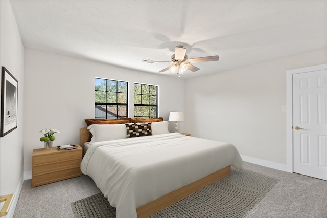 bedroom with ceiling fan, light colored carpet, and a textured ceiling