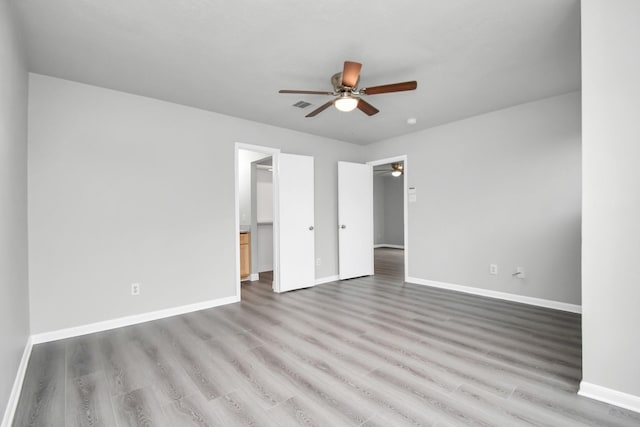 unfurnished bedroom with a walk in closet, light hardwood / wood-style floors, and ceiling fan