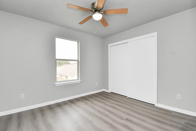 unfurnished bedroom featuring a closet, hardwood / wood-style flooring, and ceiling fan