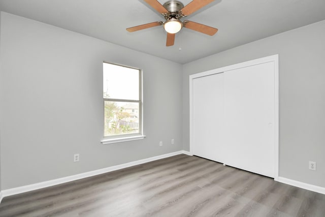 unfurnished bedroom with ceiling fan, a closet, and hardwood / wood-style flooring