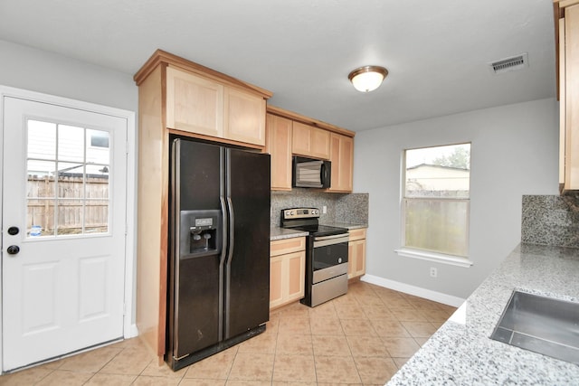 kitchen featuring black appliances, light brown cabinets, backsplash, and a wealth of natural light