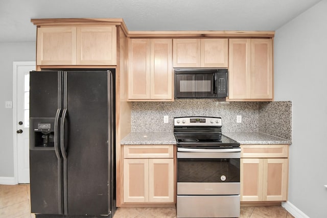 kitchen with black appliances, light brown cabinetry, tasteful backsplash, light tile patterned flooring, and light stone counters