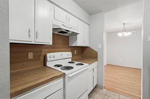 kitchen with light wood-type flooring, decorative light fixtures, an inviting chandelier, white range with electric cooktop, and white cabinetry