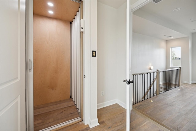 stairs with wood-type flooring and elevator