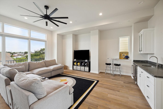 living room featuring ceiling fan, sink, and light wood-type flooring