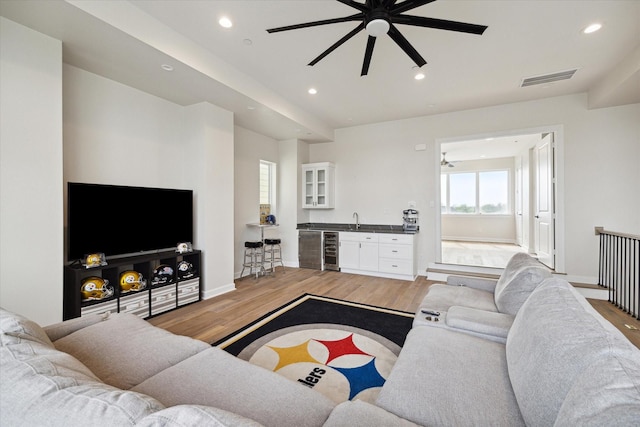 living room featuring wine cooler, ceiling fan, wet bar, and hardwood / wood-style flooring