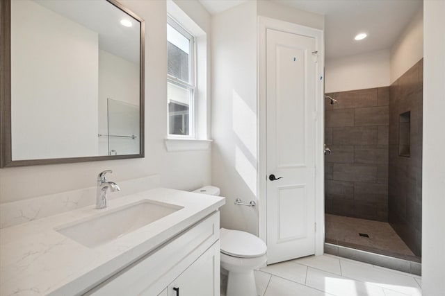 bathroom with toilet, vanity, tiled shower, and tile patterned floors