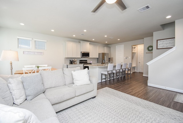 living room with dark hardwood / wood-style floors and ceiling fan